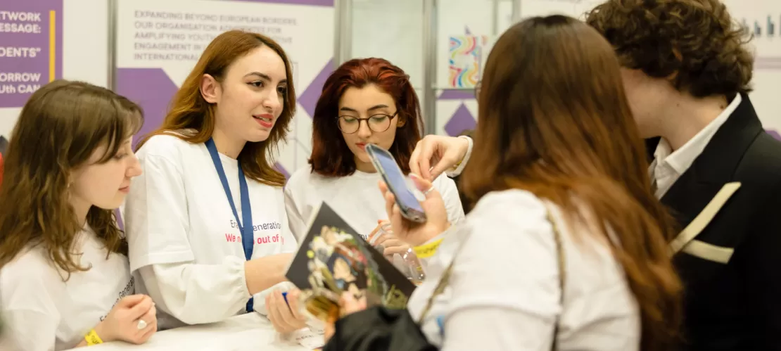 A group of people talking at a stand.