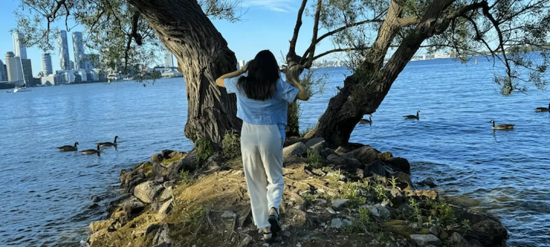 Girl running toward a tree; with the Ontario lake and the Toronto skyline in the background.