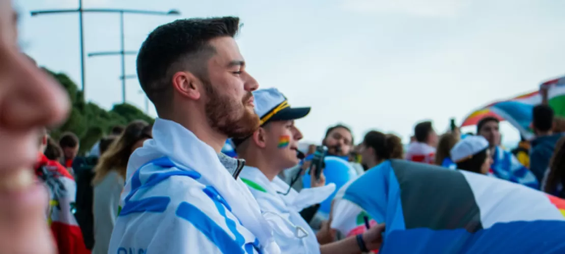 A person with a flag around them surrounded by other people in their country colours.