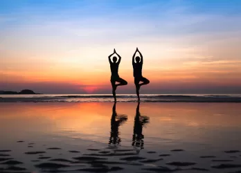 two persones doing yoga in front of the sea
