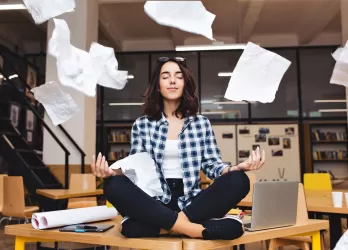 woman sit on desk with flying papers around