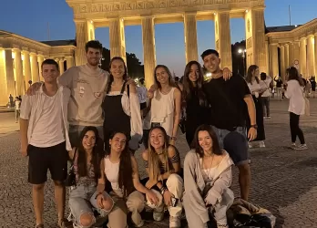 A group of international students standing in front of Brandenburger Tor in Berlin, taking a photo in the evening hours