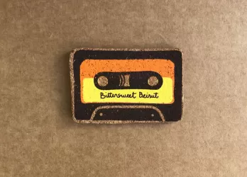 Magnet with the image of a black, orange and yellow cassette tape with the phrase "Bittersweet Beirut" in cursive font.