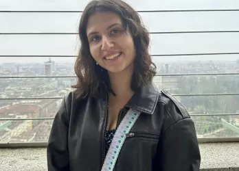 A brunette girl in a leather jacket smiling with the Torino panorama in the background