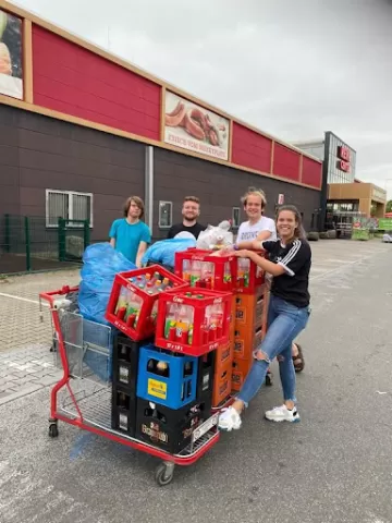 A group of people standing in front of market with a pile of boxes