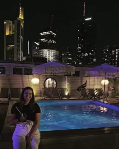 Blanka sitting next to a pool, with city lights behind her