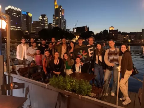 A group of young people posing to a photo with a city outline in the background