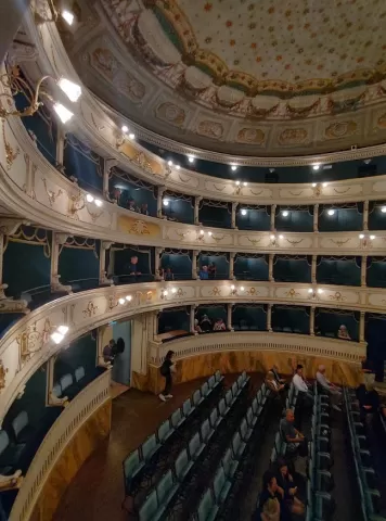 A white and blue concert hall with multiple balconies and lodges (Teatro dei Rinnovati)