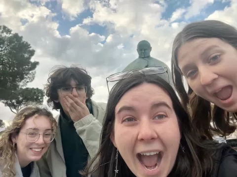 Four people standing in front of a statue, smiling