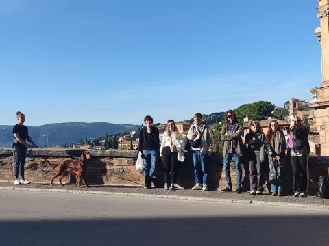 A group of people standing on the right, while a person with a dog approaches them
