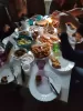 A table with a lot of food and plates on it, in the background people